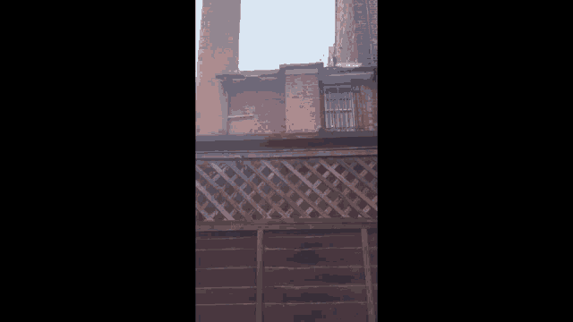 a man is standing in front of a brick building and a fence .