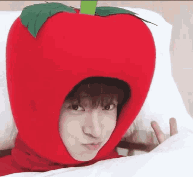 a person is wearing a red apple hat and making a face .