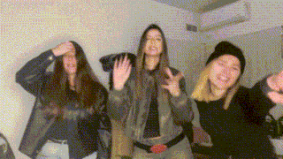 three women are standing next to each other in a room and dancing .