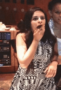 a woman in a black and white dress is covering her mouth