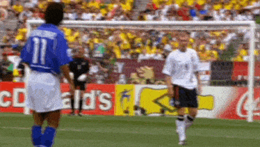 two soccer players standing on a field with a mcdonald 's sign in the background