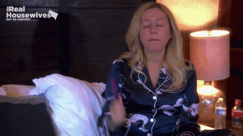 a woman is sitting on a bed with her eyes closed and the words real housewives out of context behind her