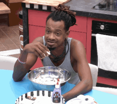 a man sitting at a table with a bowl of food and a bottle of soap