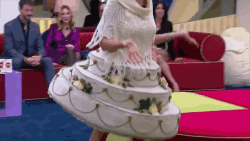 a woman in a dress that looks like a wedding cake is dancing on a stage .