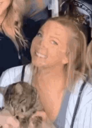 a woman is holding a cat in her lap while smiling .