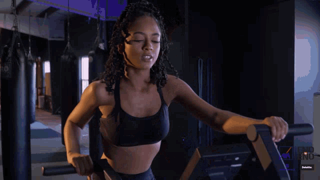 a woman is riding an exercise bike in a gym with the word delete visible