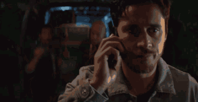 a man is talking on a cell phone while standing in a dark room