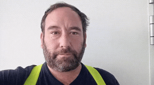 a man with a beard wears a yellow vest