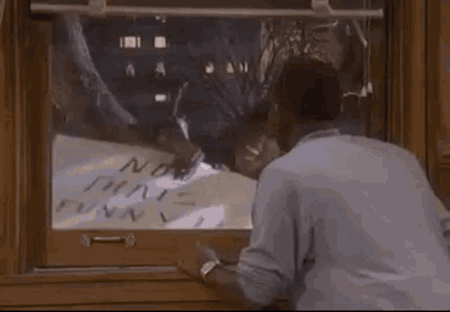 a man is holding a sign in front of a window that says `` now that 's funny ! ''