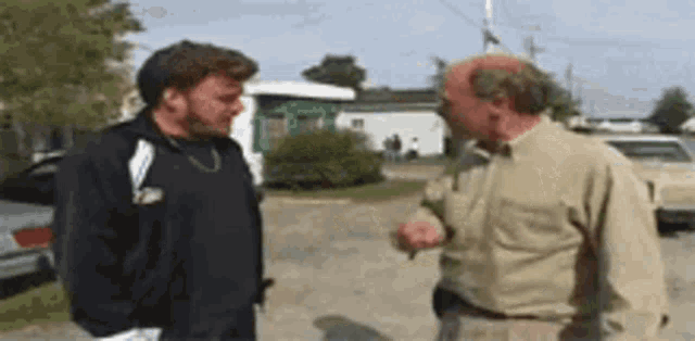 two men are standing next to each other on a street talking