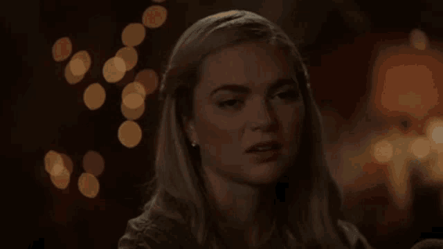 a close up of a woman 's face with a blurry background of lights .