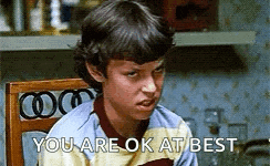 a young boy is sitting in a chair and making a funny face while saying `` you are ok at best '' .