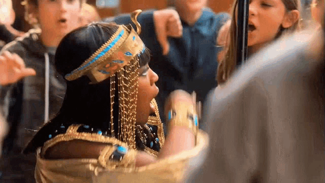 a woman dressed as a pharaoh is surrounded by a crowd of people