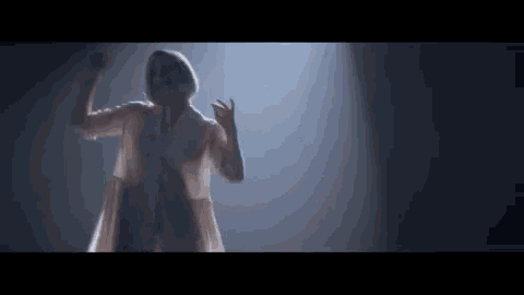 a woman in a white dress is standing in a dark room .