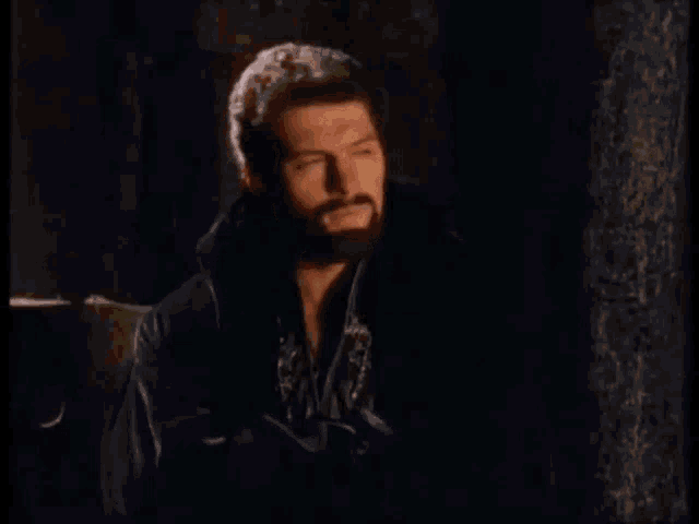 a man with a beard in a black coat says this is grotesque