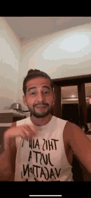 a man with a beard is wearing a white tank top that says " a true matadav "