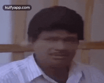 a man with a mustache is making a funny face while sitting in a chair .