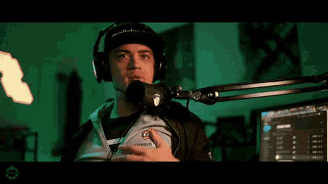 a man wearing headphones stands in front of a microphone that says stream