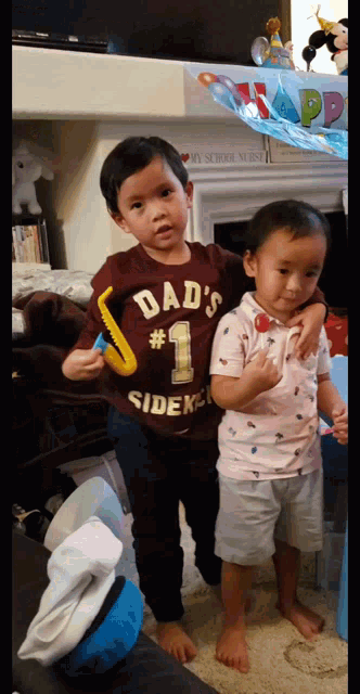 two young boys standing next to each other one wearing a dad 's # 1 shirt