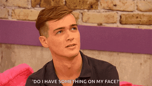 a man says " do i have something on my face " while sitting on a pink couch