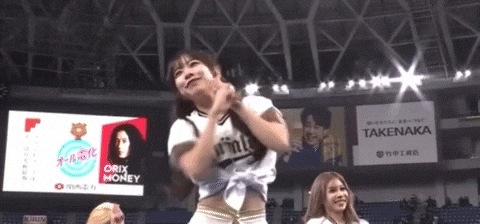 a cheerleader is dancing in front of a large screen that says takenaka on it