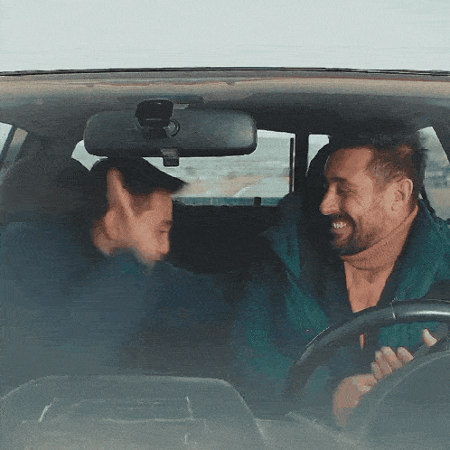 a man in a green jacket is driving a car