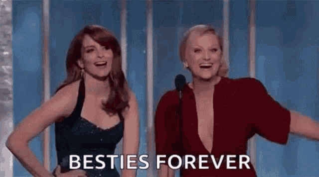 two women are standing next to each other on a stage at a awards show .