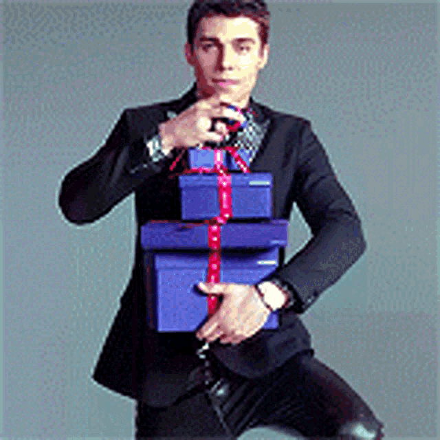 a man in a suit is holding a stack of blue gift boxes