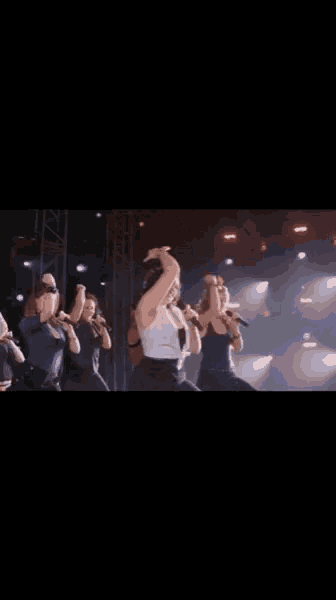 a group of women are singing and dancing on a stage .