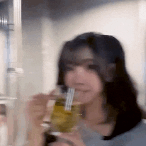 a woman is drinking from a glass with a fork in it .