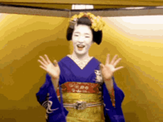 a woman in a blue kimono is waving her hands in front of a gold wall