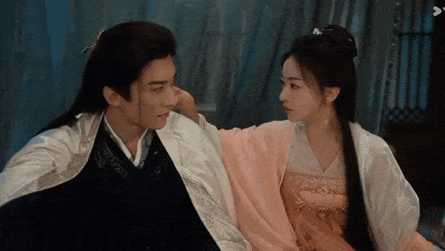 a man and a woman are sitting next to each other in a room .