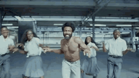 a shirtless man is dancing with a group of people in a parking garage .