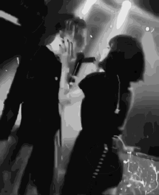 a woman singing into a microphone while standing next to a man