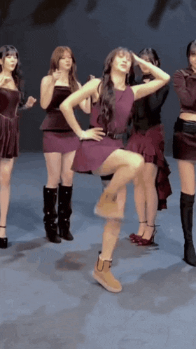 a woman in a purple dress is standing on one leg in front of a group of girls