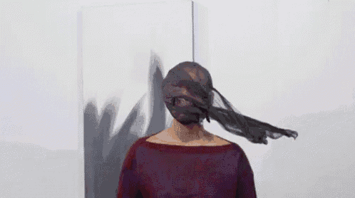 a woman is standing in front of a painting with her face wrapped in a veil .