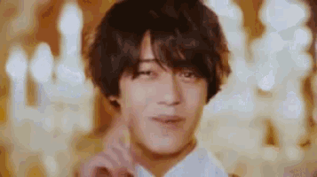 a close up of a young man making a funny face in front of a blurred background .