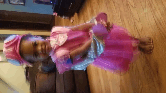 a little girl is wearing a pink dress and hat