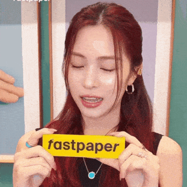 a woman with red hair is holding a fastpaper sign in her hands