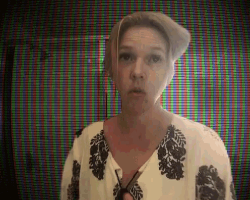a woman wearing a hat and a white shirt is standing in front of a screen .