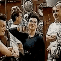 a group of people are standing next to each other in front of a wall of plates .