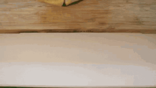 a piece of dough is sitting on a wooden cutting board