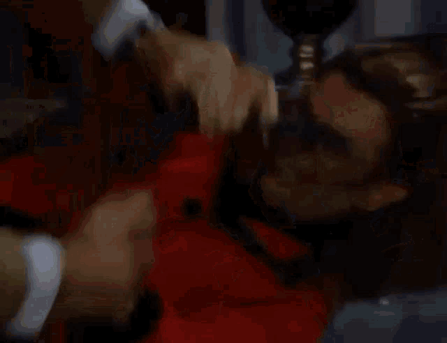 a man in a suit is fighting a woman in a red sweater in a living room .