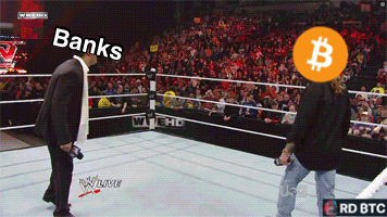 a man in a suit stands in a wrestling ring next to a man with a bitcoin logo on his face