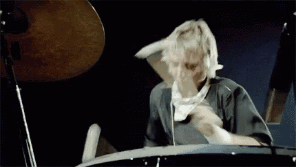 a man is playing drums in a dark room with a microphone in the background .