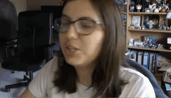 a woman wearing glasses is sitting in front of a book shelf