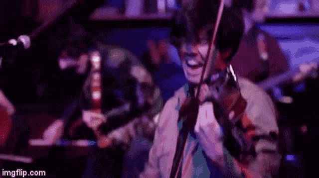 a man is playing a violin in front of a microphone while another man plays a guitar .