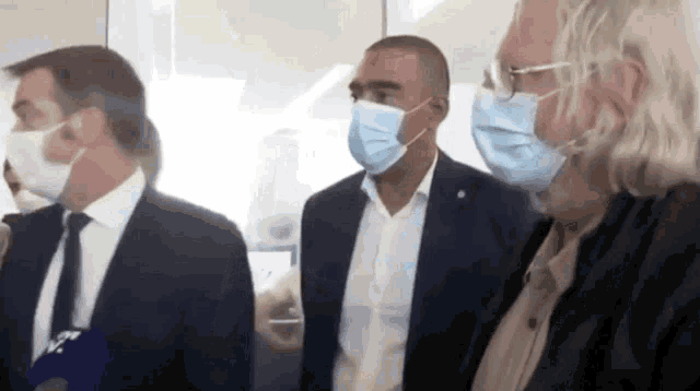 a group of men wearing face masks are standing in a room