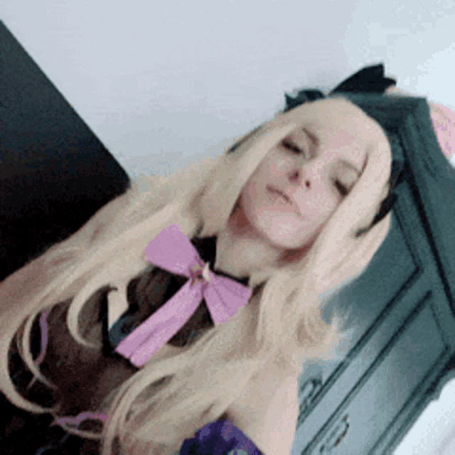 a woman with blonde hair is wearing a purple bow
