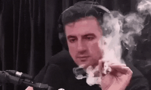 a man is smoking a cigarette in front of a microphone in a studio .